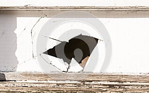 Hole with multiple cracks in a white wooden panel