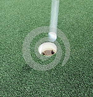 Hole in one with golf ball at speed.
