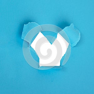 Hole in paper blue background torn damaged for design