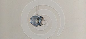 A hole in a plastered wall. A blue construction mesh for finishing works is visible in the hole