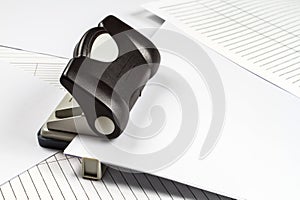 A hole punch on a background of paper and forms.