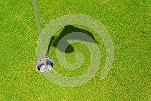 Hole on putting green with flag stick and shadow of flag. hole or target point for success concept . copy space for your text