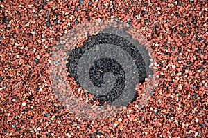 Hole in a red rubber coating on the playground.