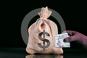 Hole-ridden burlap sack with dollars and hand in glove pulls money. Take away the budget.