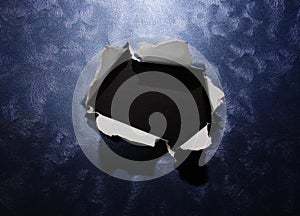 Hole ripped in textured metallic background surface with black copy space