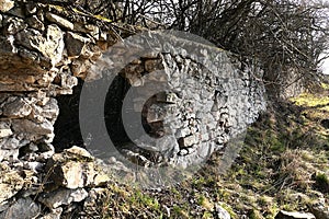 A hole in stone wall of abandoned jewish cemetery. Spring morning sunshine.