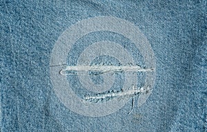 Hole and Threads on Denim Jeans. Ripped Destroyed Torn Blue jeans background
