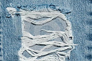 Hole and Threads on Denim Jeans. Ripped Destroyed Torn Blue jeans background.