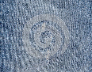 Hole and Threads on Denim Jeans. Ripped Destroyed Torn Blue jeans background. Close up blue jean texture