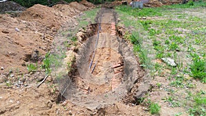 A hole was dug at the edge of a city park to repair and replace electrical and telephone cables. A brick lining is being placed un