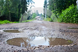 Holes and pothole on a rural road after rain in spring