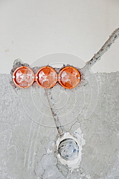 Holes in the wall with orange wires for socket switches. Man installing electricity. Maintenance repair works renovation in the