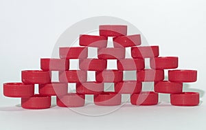 Holey wall pattern of red ribbed plastic bottle caps, relying on