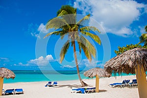 Holguin, Cuba, Playa Esmeralda. Beautiful Caribbean sea turquoise blue color and palm trees on the beach. Sun loungers and umbrell