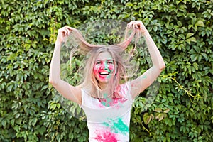 Holi festival, holidays and people concept - young woman having a fun at the festival of holi