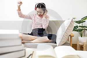 Holiday activities at home,Happy carefree asian teenage girl listening to music on mobile phone,singing,dancing or reading books,