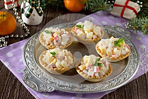 Holiday appetizer: tartlets with crab sticks, cheese and pineapple on Christmas or New Year holiday table