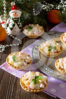 Holiday appetizer: tartlets with crab sticks, cheese and pineapple on Christmas or New Year holiday table