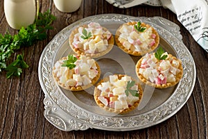 Holiday appetizer: tartlets with crab sticks, cheese and pineapple on a wooden table