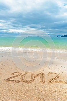 Holiday background, 2012 written on sand of beach