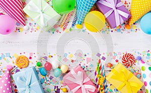 Holiday background with balloons, gift boxes and confetti. Birthday and party supplies on white table top view. Banner format