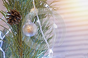 Holiday background. Christmas tree closeup decorated with white ball and real cone