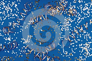 Holiday background with confetti and ribbons on classic blue