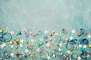 Holiday background decorated colorful confetti, star, candy and streamer on blue vintage table top view. Flat lay. Festive border.