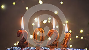 Holiday background Happy New Year 2021. Digits of year 2021 made by burning gold candles on red festive sparkling