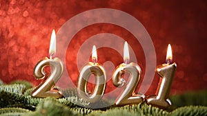 Holiday background Happy New Year 2021. Digits of year 2021 made by burning gold candles on red festive sparkling background