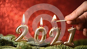 Holiday background Happy New Year 2021. Digits of year 2021 made by burning gold candles on red festive sparkling background.