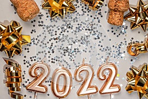 Holiday background Happy New Year 2022. Digits of year 2021 made by burning gold candles on red festive sparkling