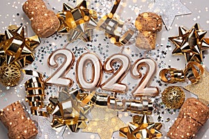 Holiday background Happy New Year 2022. Digits of year 2021 made by burning gold candles on red festive sparkling background