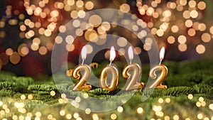 Holiday background Happy New Year 2022. Digits of year 2022 made by burning gold candles on red festive sparkling background