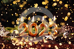 Holiday background Happy New Year 2023. Digits of year 2023 made by burning gold candles on red festive sparkling