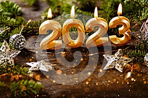 Holiday background Happy New Year 2023. Digits of year 2023 made by burning gold candles on red festive sparkling