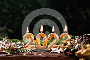 Holiday background Happy New Year 2023. Digits of year 2023 made by burning gold candles on red festive sparkling