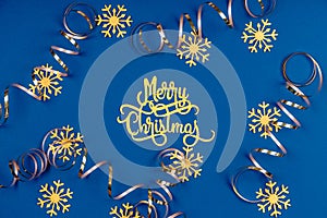 Holiday background with Merry Christmas wording, golden snowflakes, and ribbons on classic blue