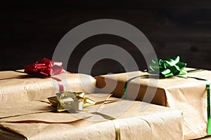 Holiday banner with gift boxes, covered by brown craft paper, tied by red, yellow and green mettalic bows and ribbons. Copy space