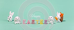 Holiday banner Happy Easter wooden words with decorative Easter bunnies on a turquoise background