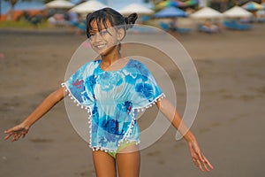 Beach lifestyle portrait of young beautiful and happy Asian child girl 8 or 9 years old with cute double buns hair style playing