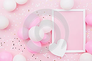 Holiday or birthday mockup with frame, pastel balloons, heart and confetti on pink table top view. Flat lay composition.