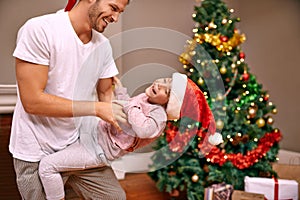 Holiday bonding moments. A father tickling his son next to a christmas tree.