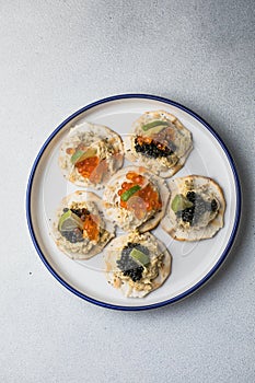 Holiday canapes with red and black caviar, on crackers festive silver Christmas decoration, copy space, selected focus, narrow