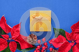 Holiday card - red flower poinsettia, fir cone, Christmas decorations on blue background. Flat lay, top view