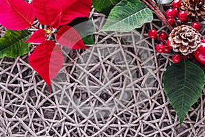 Holiday card - red flower poinsettia, fir cone, Christmas decorations on wicker straw gray background. Flat lay, top view, copy