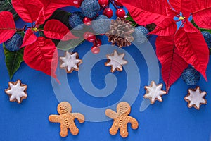 Holiday card - red flower poinsettia, stars, gingerbread  cookies men on blue background. Christmas decorations, flat lay, top