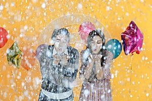 Holiday Celebrate, Christmas and New year party concept. Portrait of asian man and woman blowing silver paper confetti with