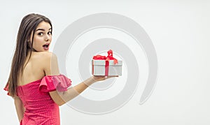 Holiday celebration concept. Curious young woman holding a present box eager to fing out wht is inside. photo