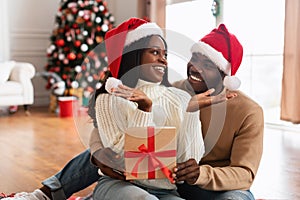 Portrait of happy black family celebrating Christmas giving present